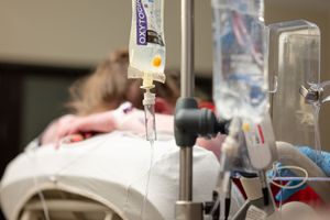 Medical staff in protective gear attend to patients in a hospital intensive care unit during treatment.