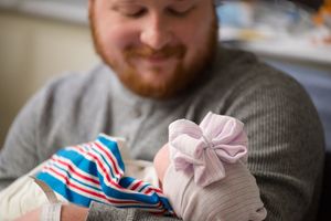 Medical professional wearing latex gloves handles a red white and blue striped cloth in a clinical setting.