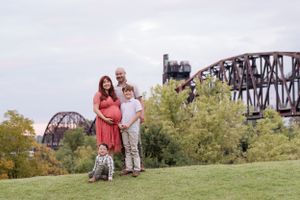A group stands on a grassy hill overlooking historic railroad bridges on an overcast day.