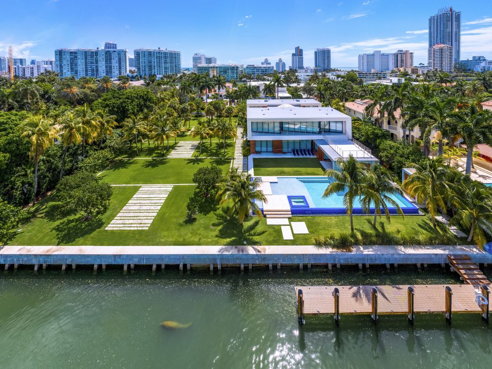 Aerial view of waterfront modern mansion with pool and private dock in Miami.