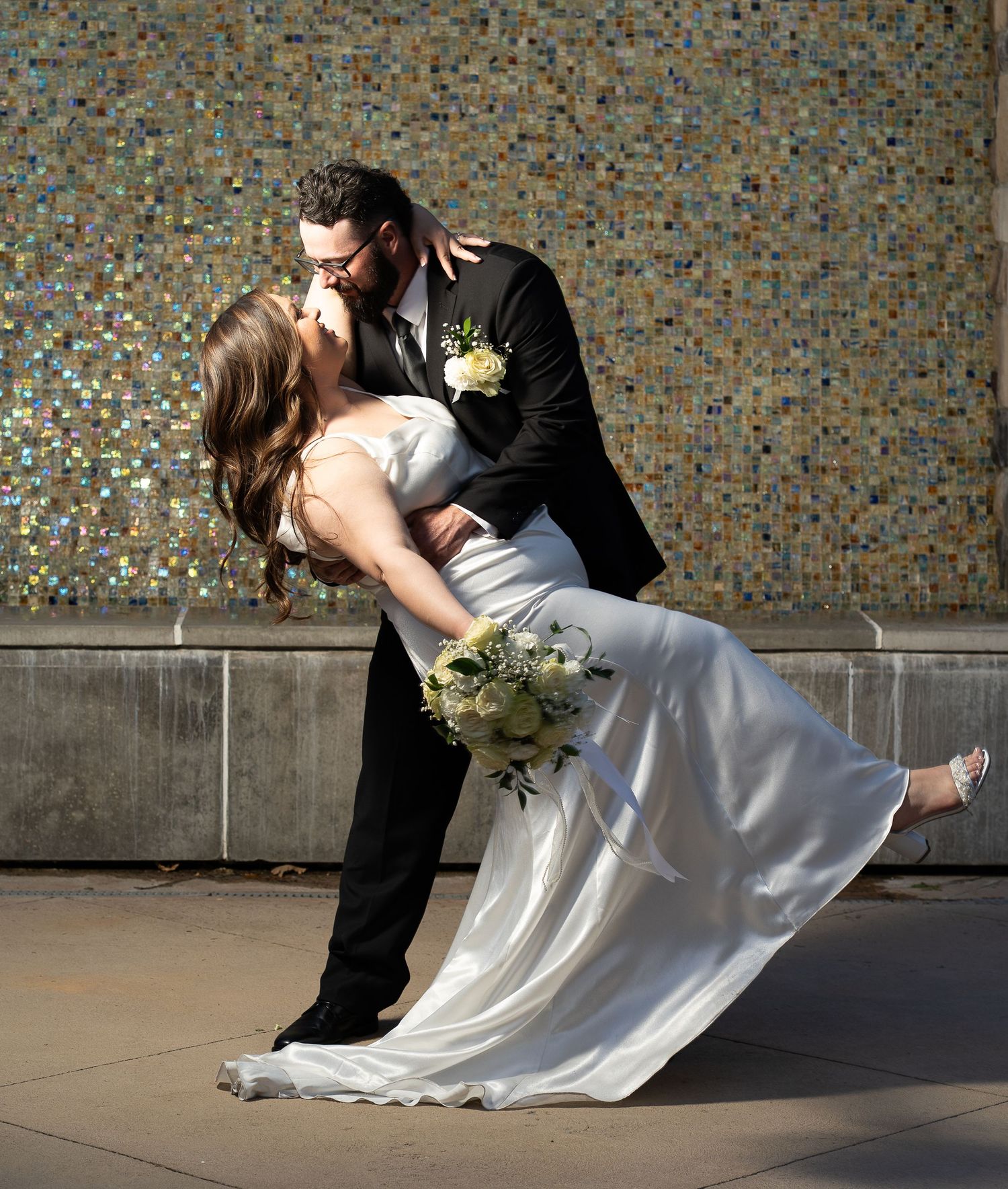 Married couple dipping on their wedding day in front of the waterfall located at the four seasons venue in Cache Valley.