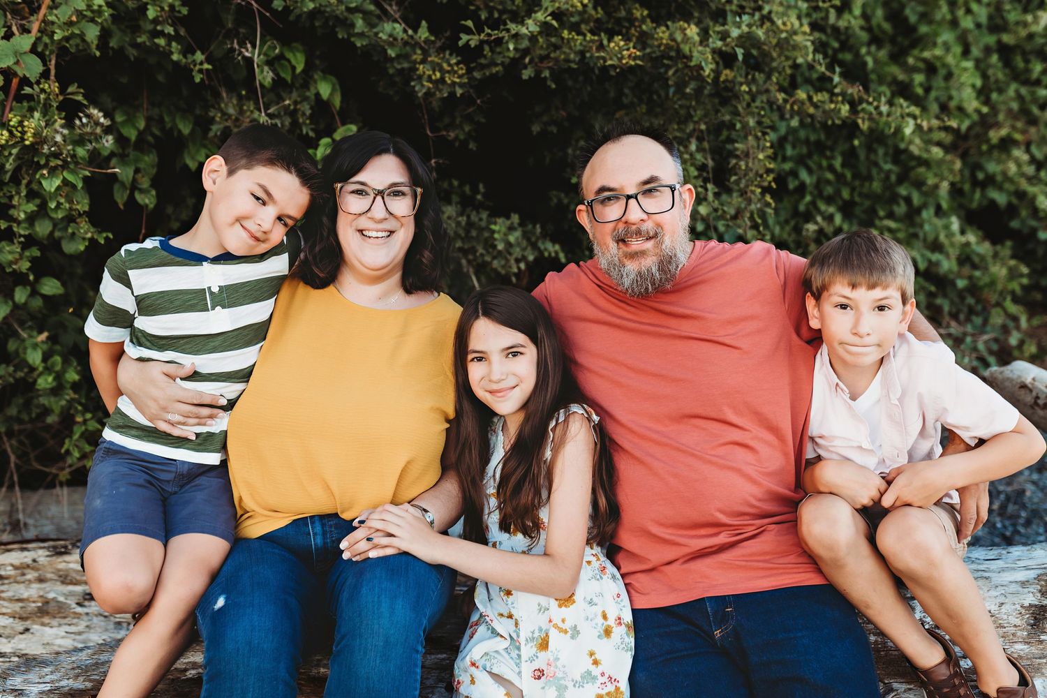 Family wearing an orange, yellow, green striped color palette sitting on a log