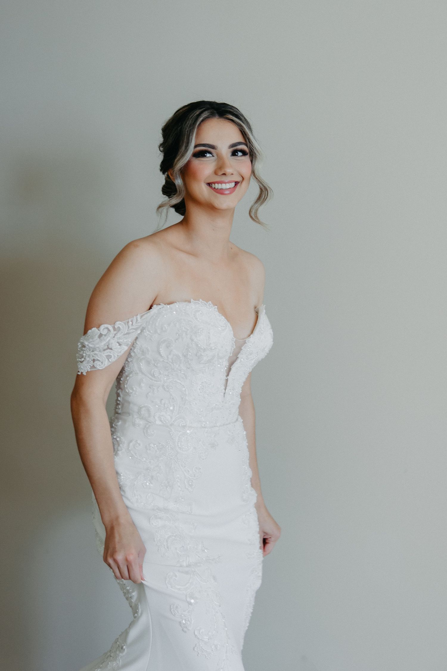 Stunning white wedding gown with off-shoulder lace details and fitted silhouette.