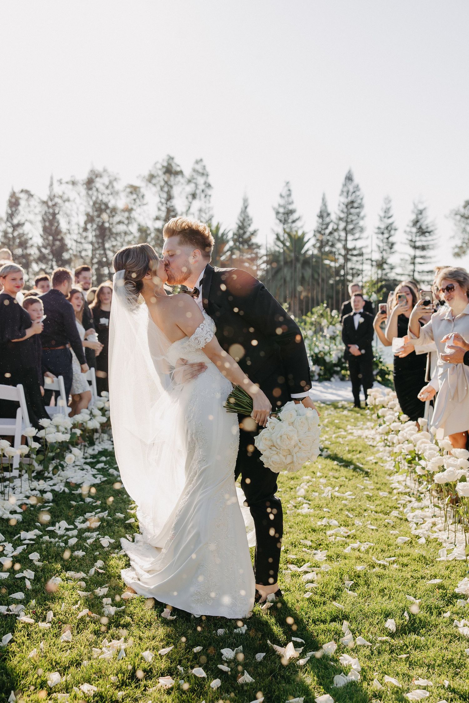 Bride and groom share romantic moment during confetti shower at outdoor wedding ceremony.