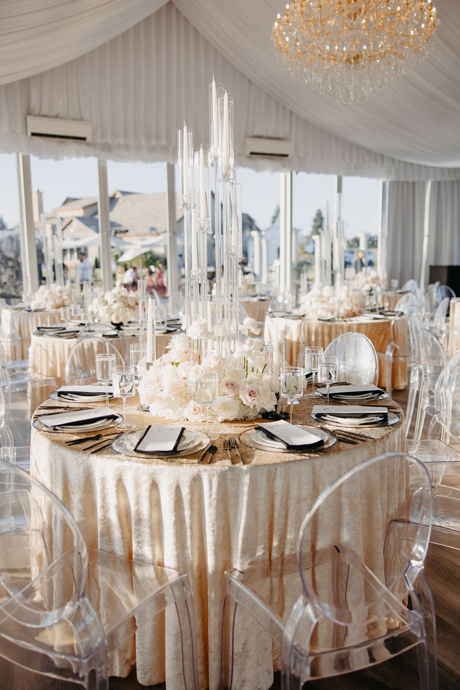Luxurious wedding reception with crystal centerpieces and cream linens under draped white tent.