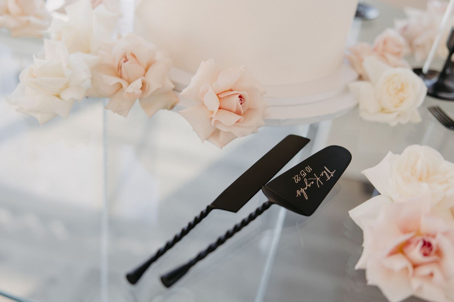 Black wedding cake servers decorated with delicate pink roses.