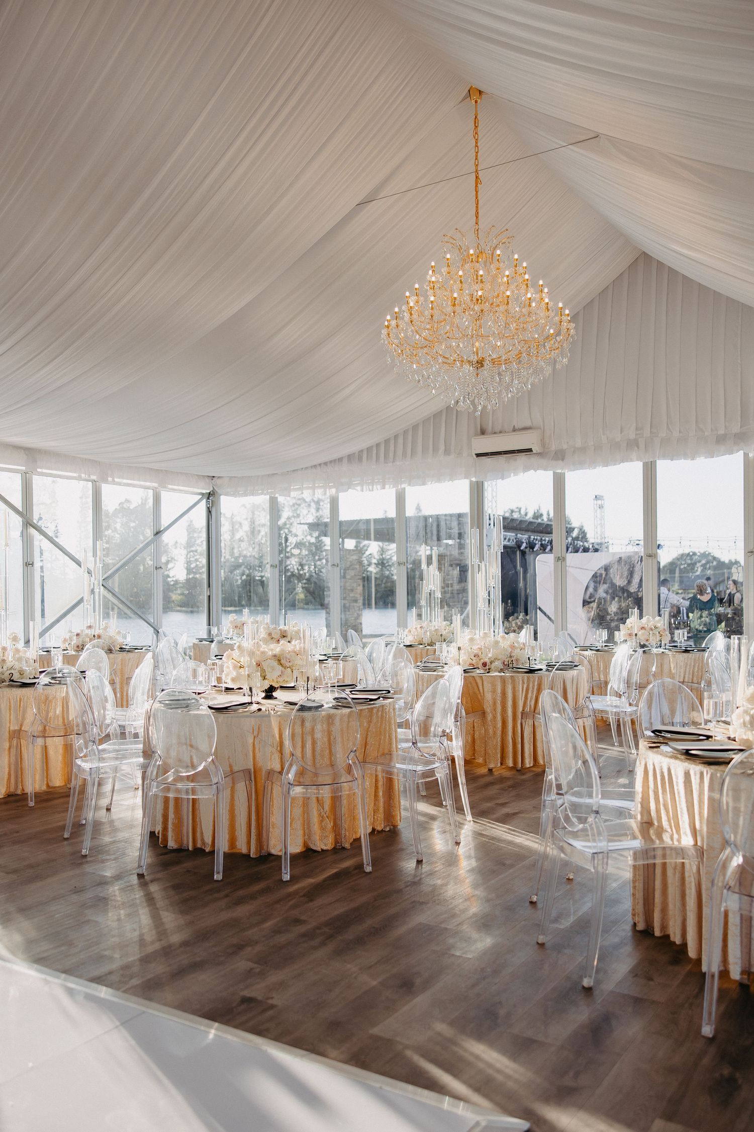 Sophisticated wedding reception space with gold chandelier and lucite chairs.