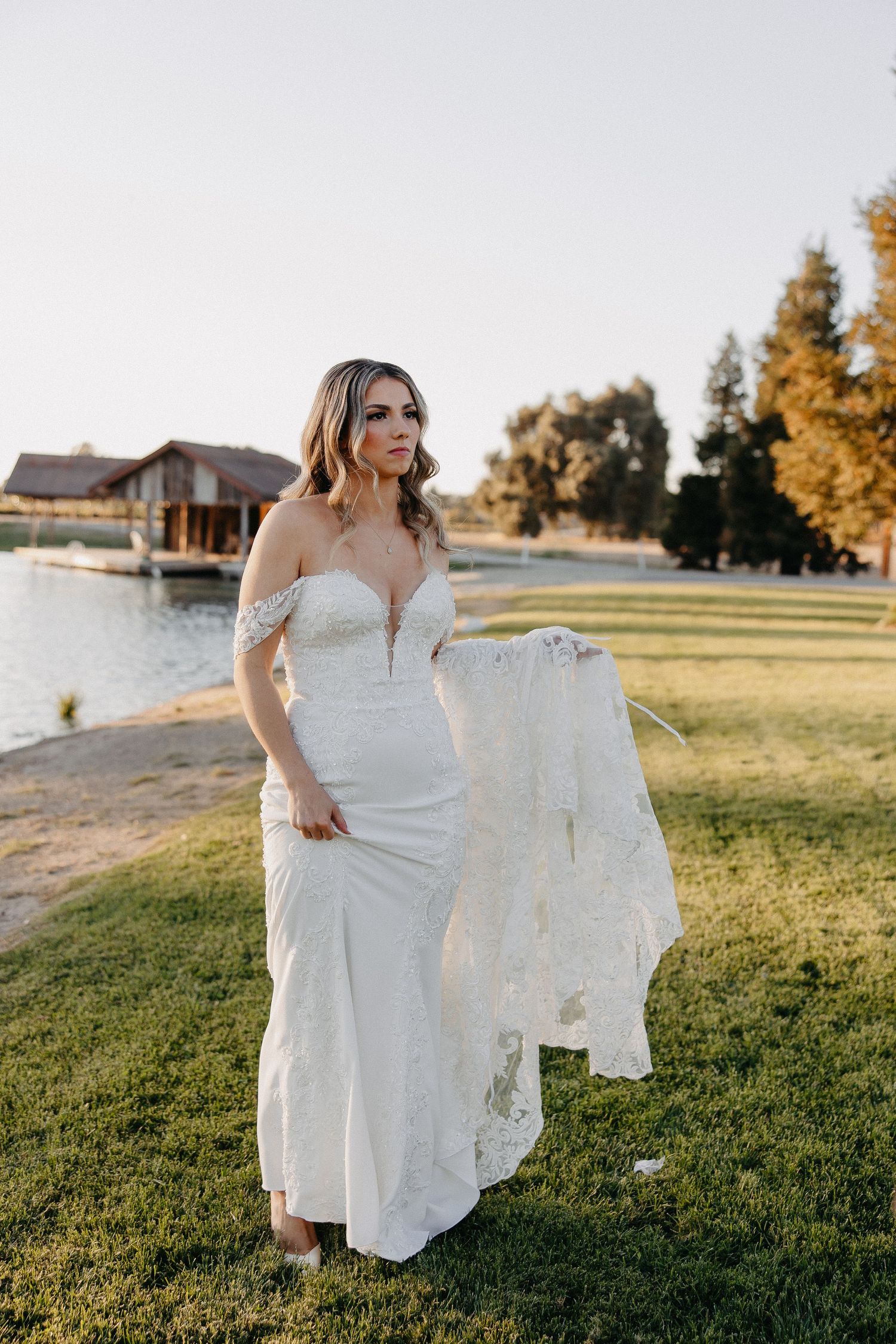 Wedding scene at sunset by lakeside venue with natural backdrop.