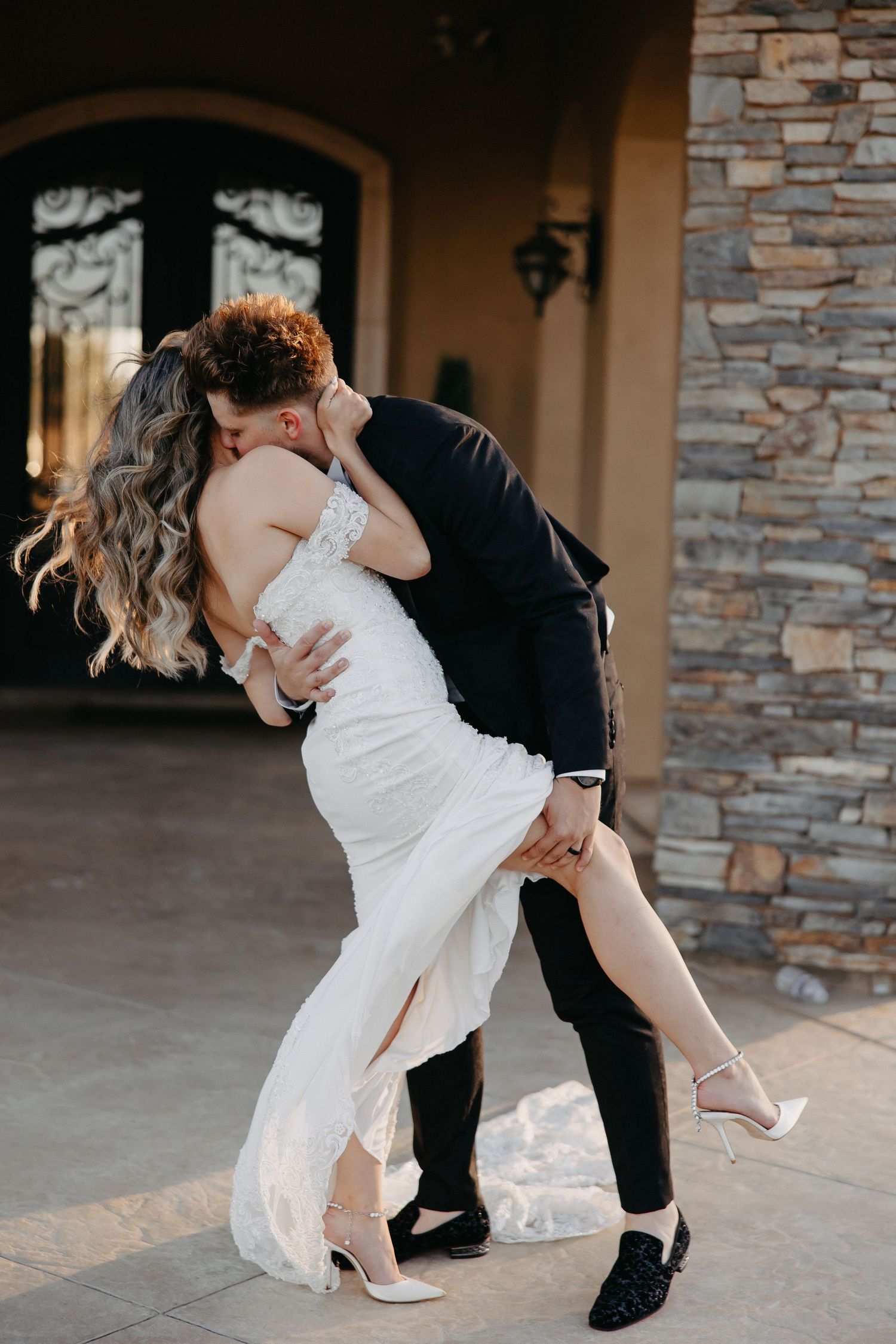 Intimate dance pose captured against stone and stucco architectural backdrop.