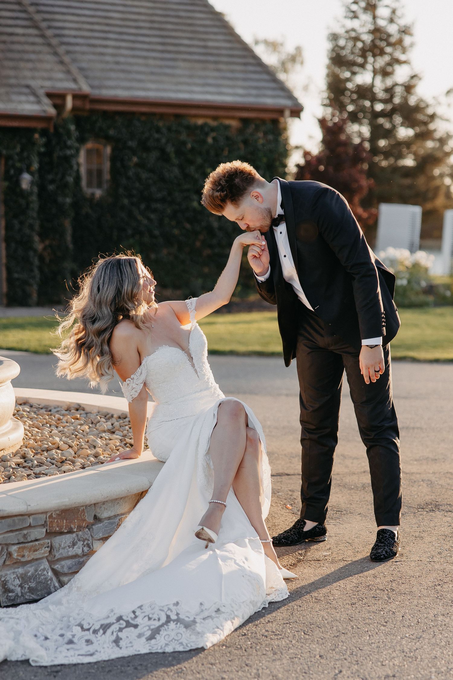 A tender moment between newlyweds by a stone wall at sunset.