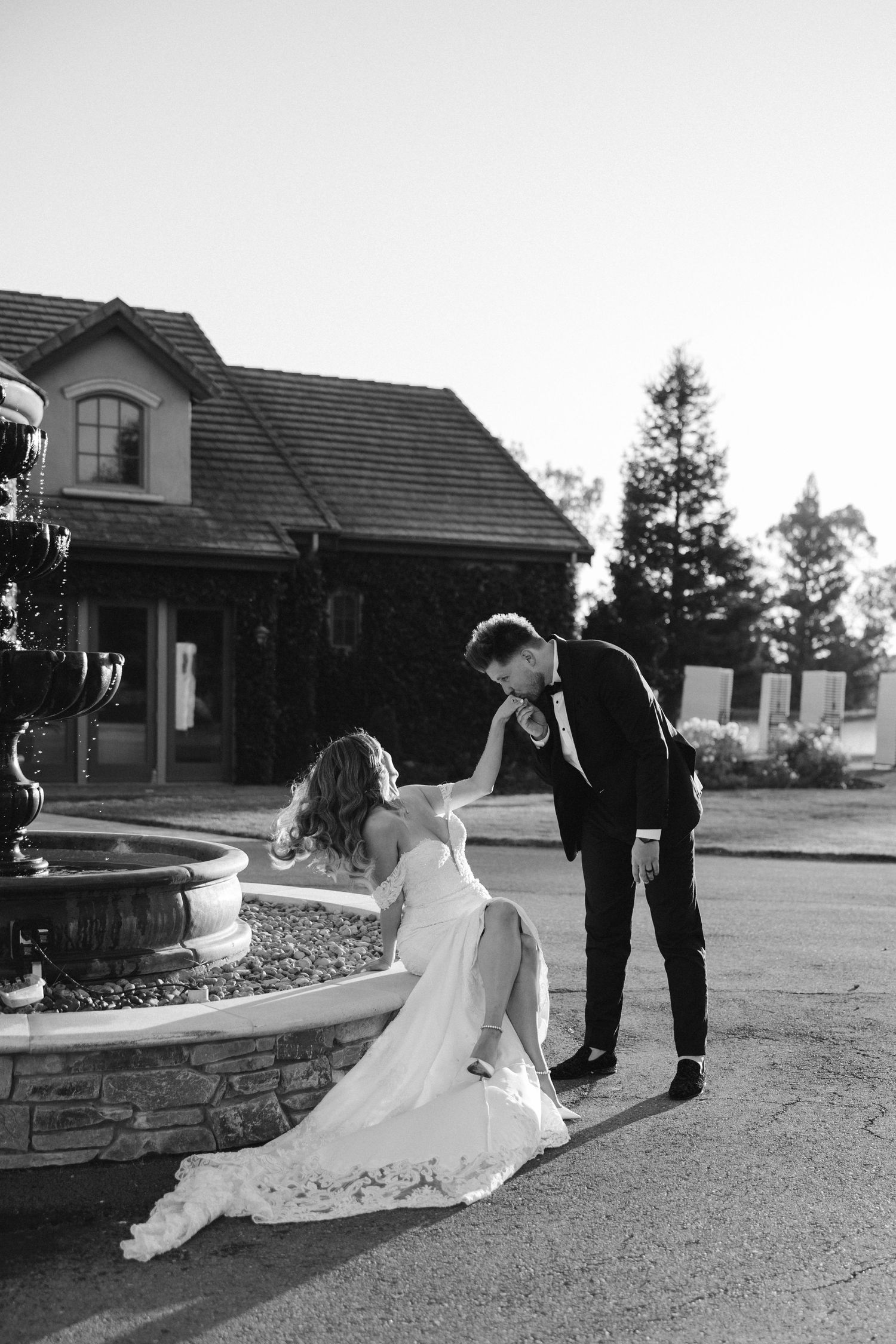 A black and white wedding photo captured near a stone fountain.