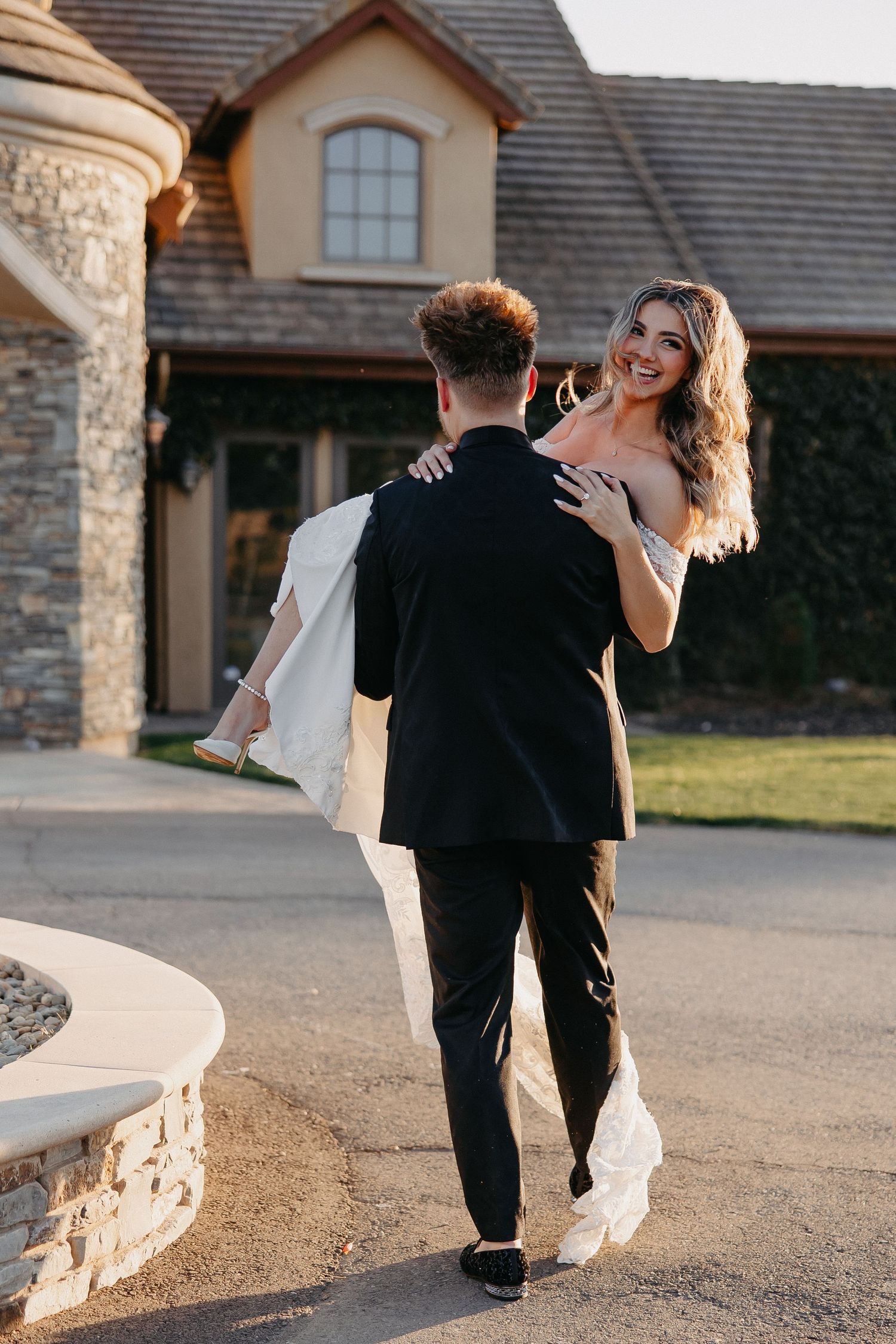 A romantic wedding lift pose captured in front of a stone building.