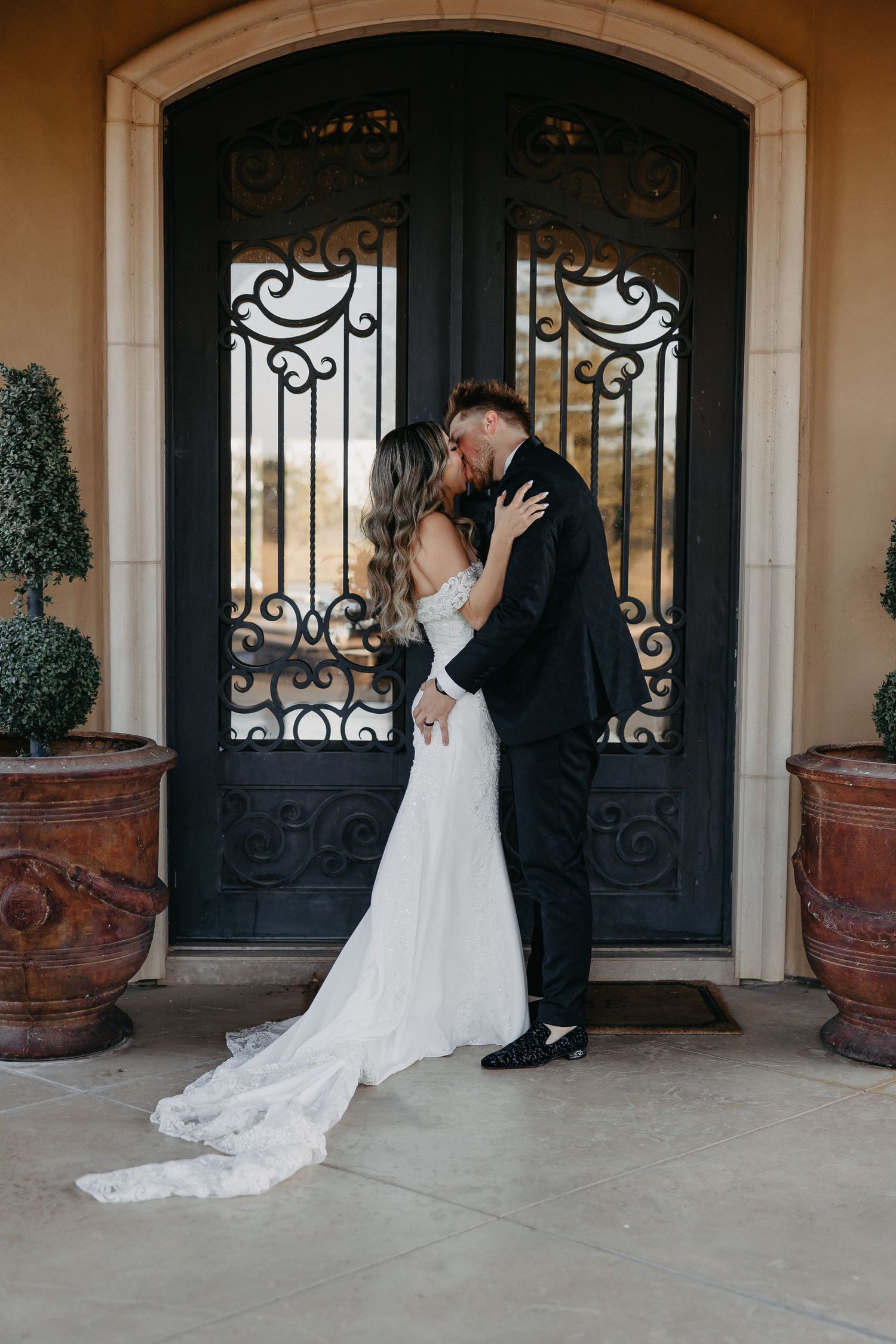Romantic moment in front of ornate black iron doors during wedding photoshoot.