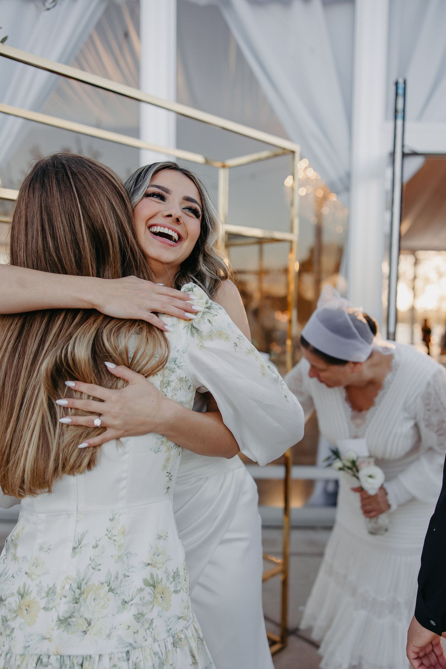 Wedding guests share emotional hugs and embraces during a reception celebration.