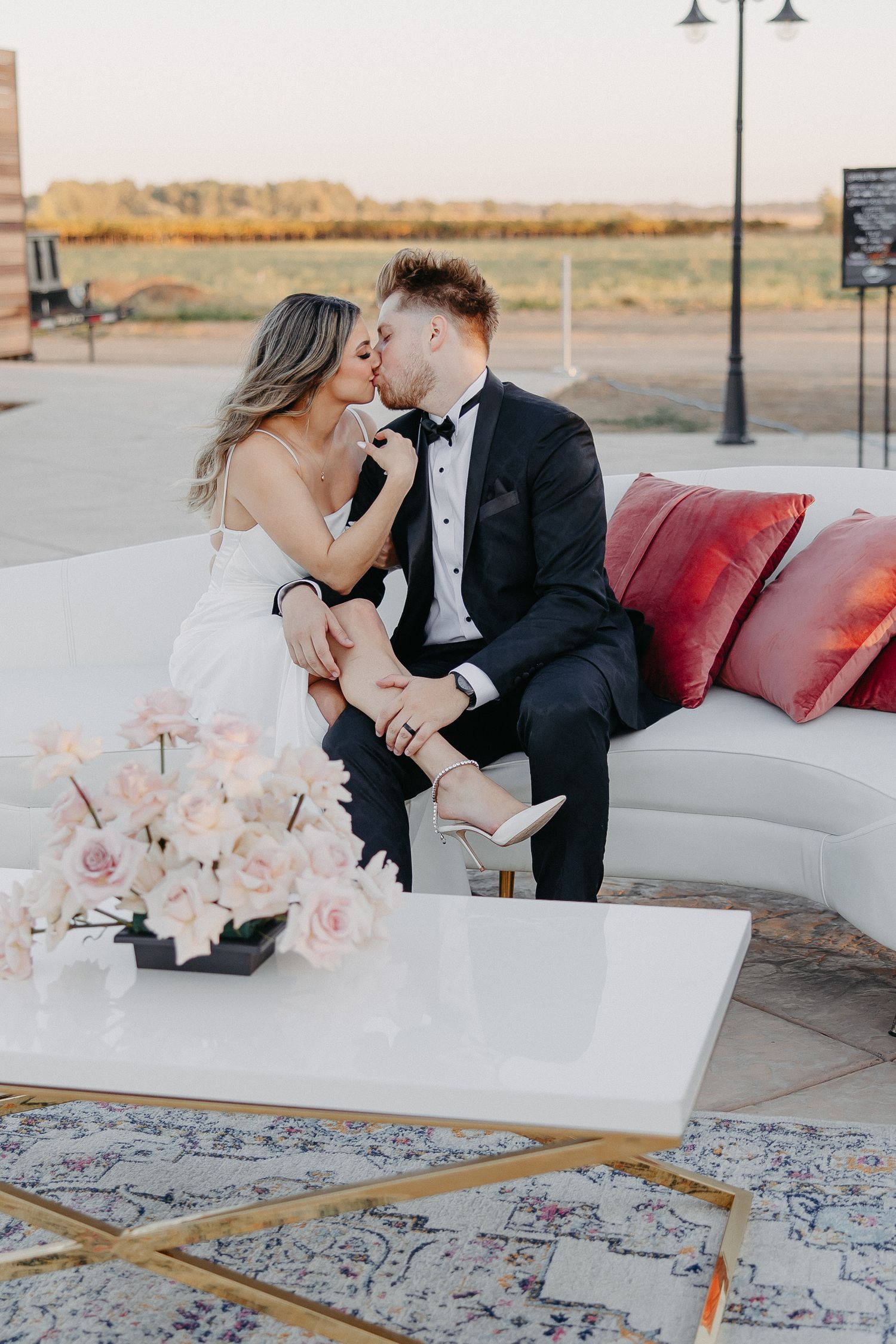 A romantic moment captured on a white sofa with pink roses and elegant decor.