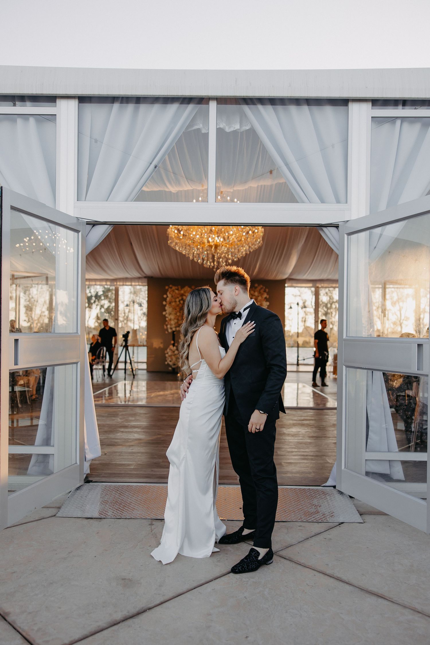 An elegant wedding venue entrance features white draping and a stunning crystal chandelier.