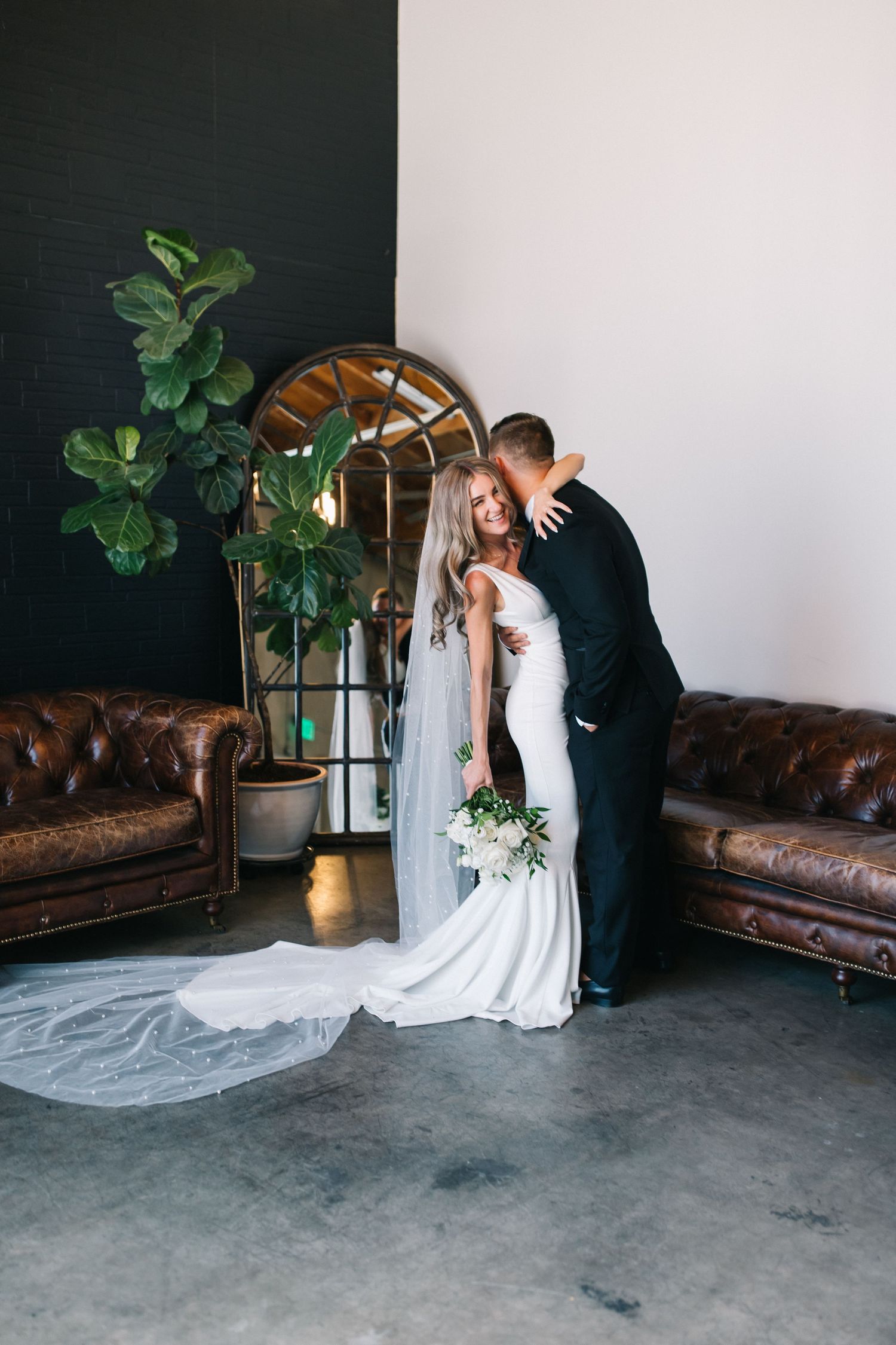 Romantic wedding portrait with fiddle leaf fig plant and arched mirror decor.