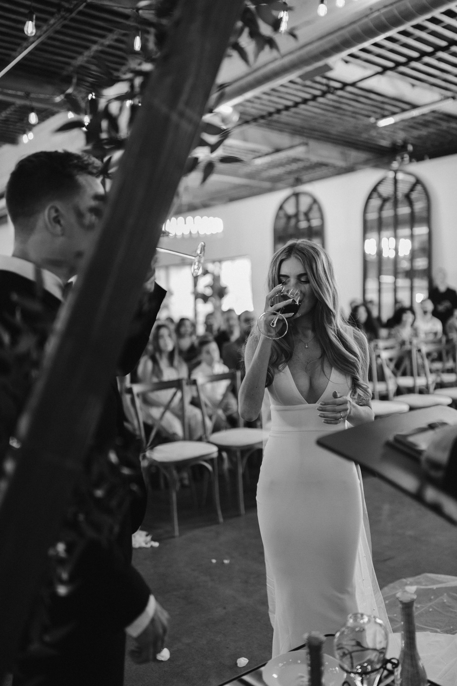 Black and white photo of emotional wedding moment under venue's industrial ceiling.