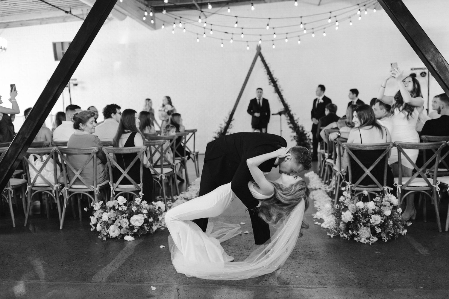 Dramatic dip during first dance at modern wedding reception with geometric backdrop.