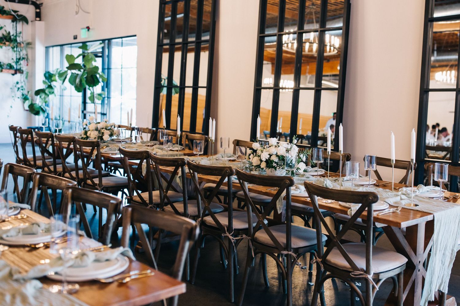 Modern restaurant reception setup with cross-back chairs and elegant table settings.