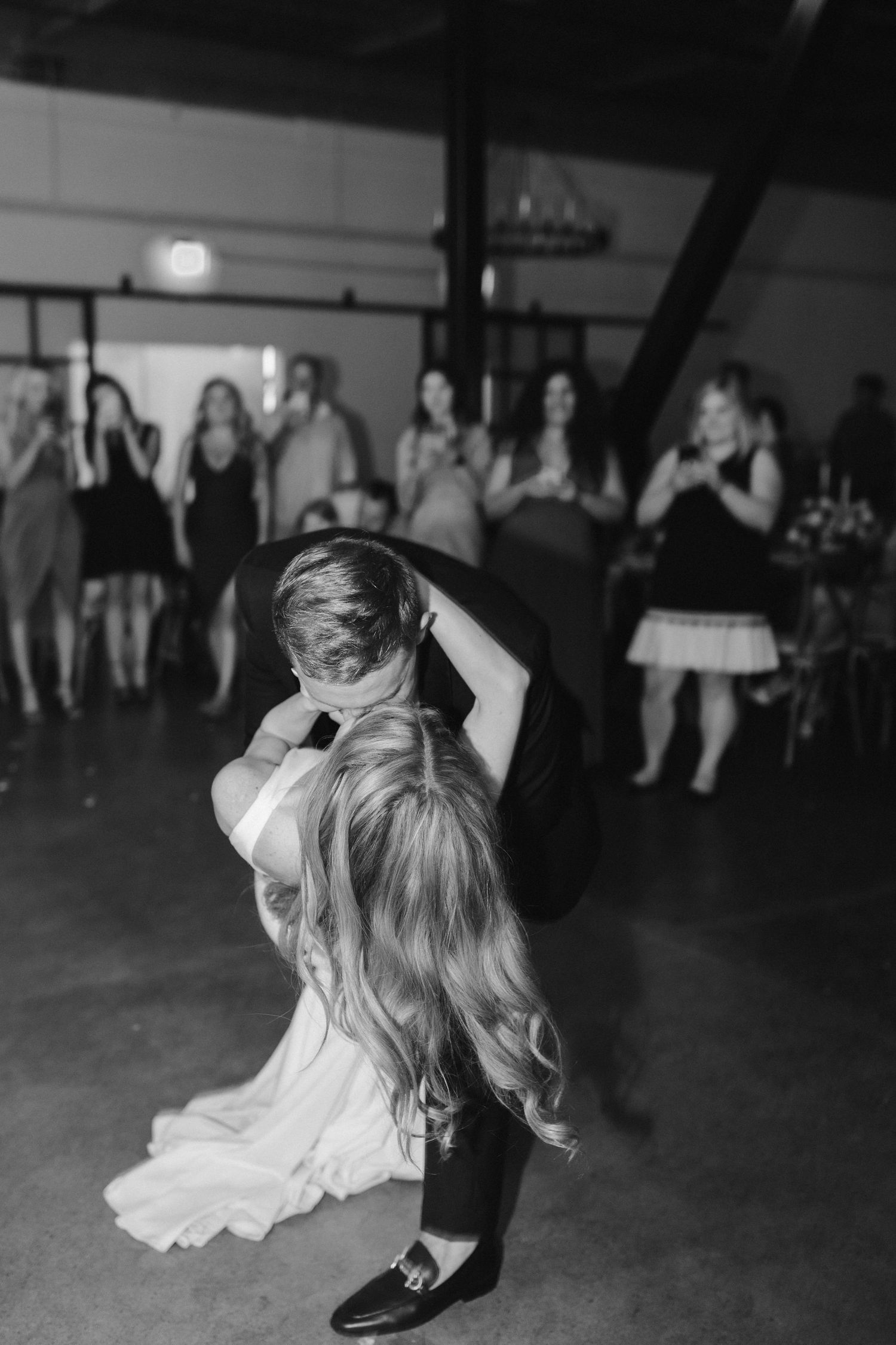Black and white photo of wedding couple performing romantic dip dance move.