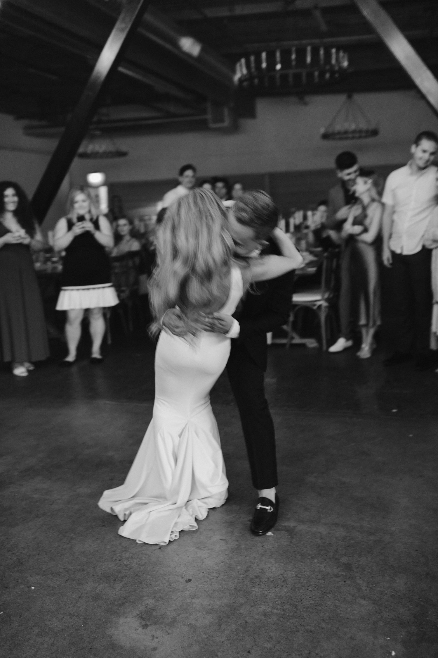 Black and white photo of wedding couple dancing intimately on reception dance floor.