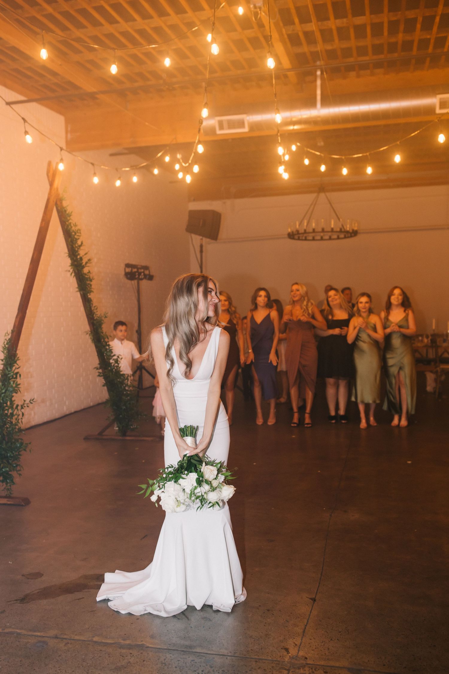 Beautiful bride holding a white floral bouquet stands alone during her wedding reception.