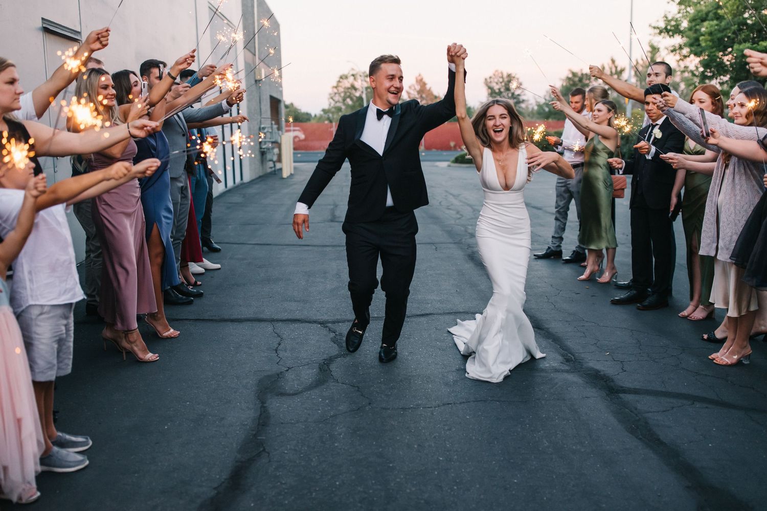 Jubilant couple celebrating while walking through a crowd of cheering wedding guests.