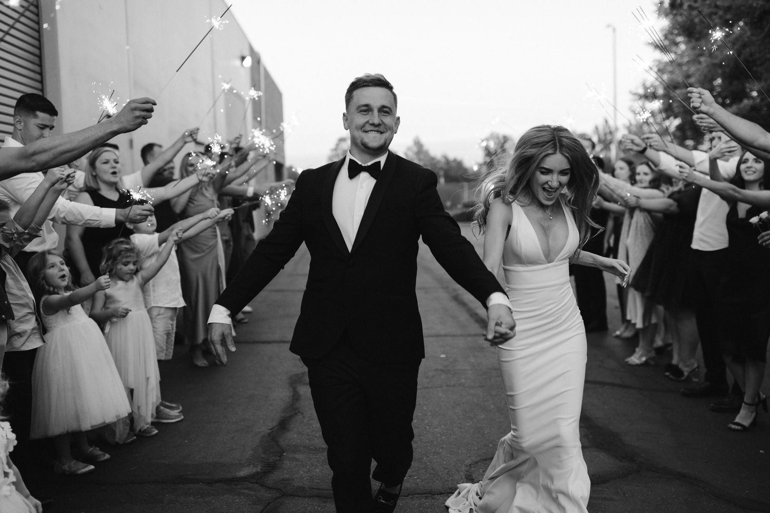 Black and white photo of newlyweds making their celebratory exit through cheering guests.