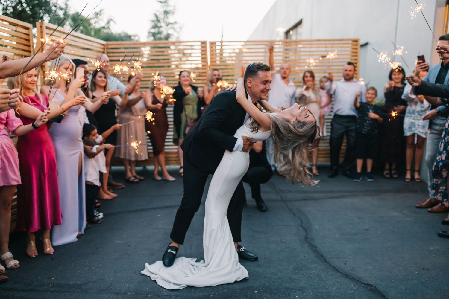 Wedding couple performs a romantic dip during their celebration as guests watch and cheer.