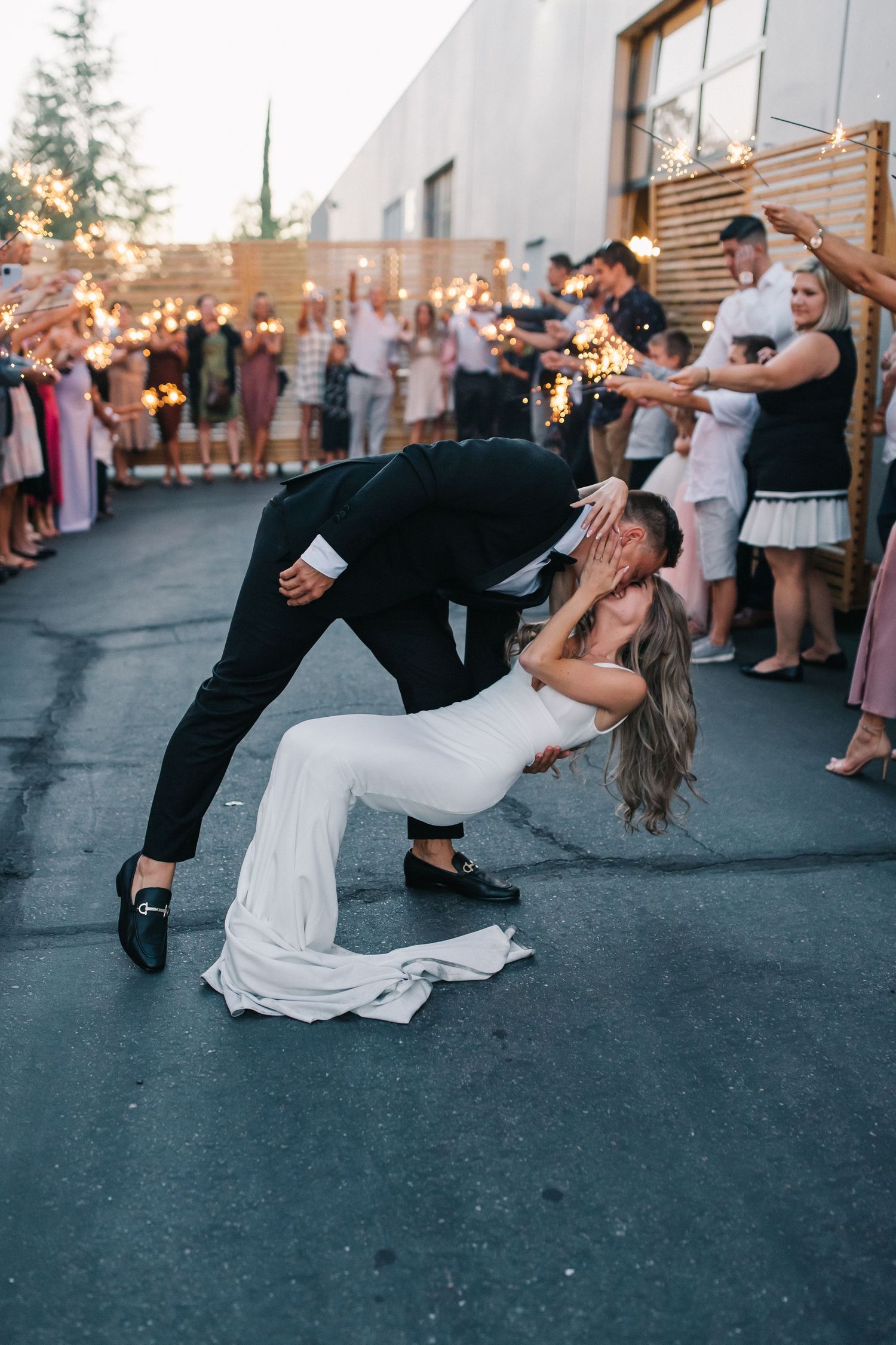 Couple performs romantic dip kiss during their outdoor wedding celebration.