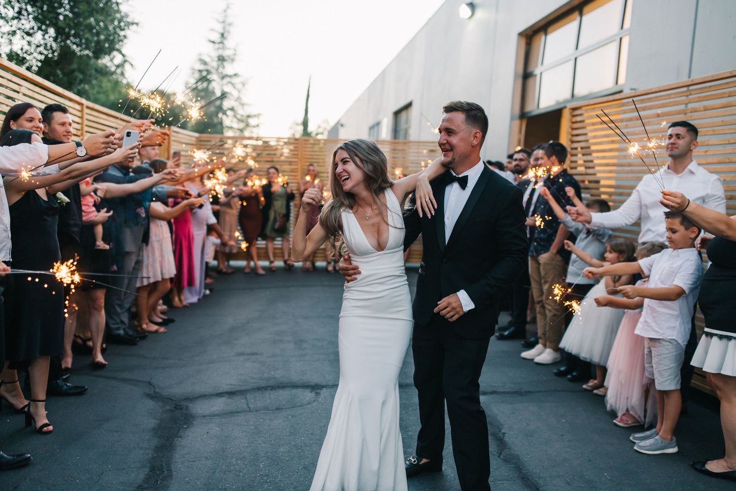 Newlyweds celebrating with sparkler exit among guests in elegant outdoor wedding setting.