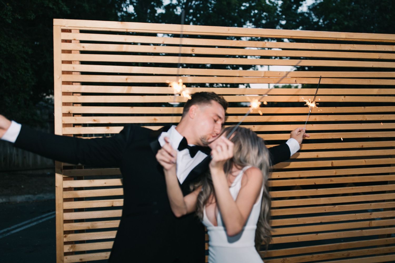 Happy couple dances with sparklers during nighttime wedding celebration.