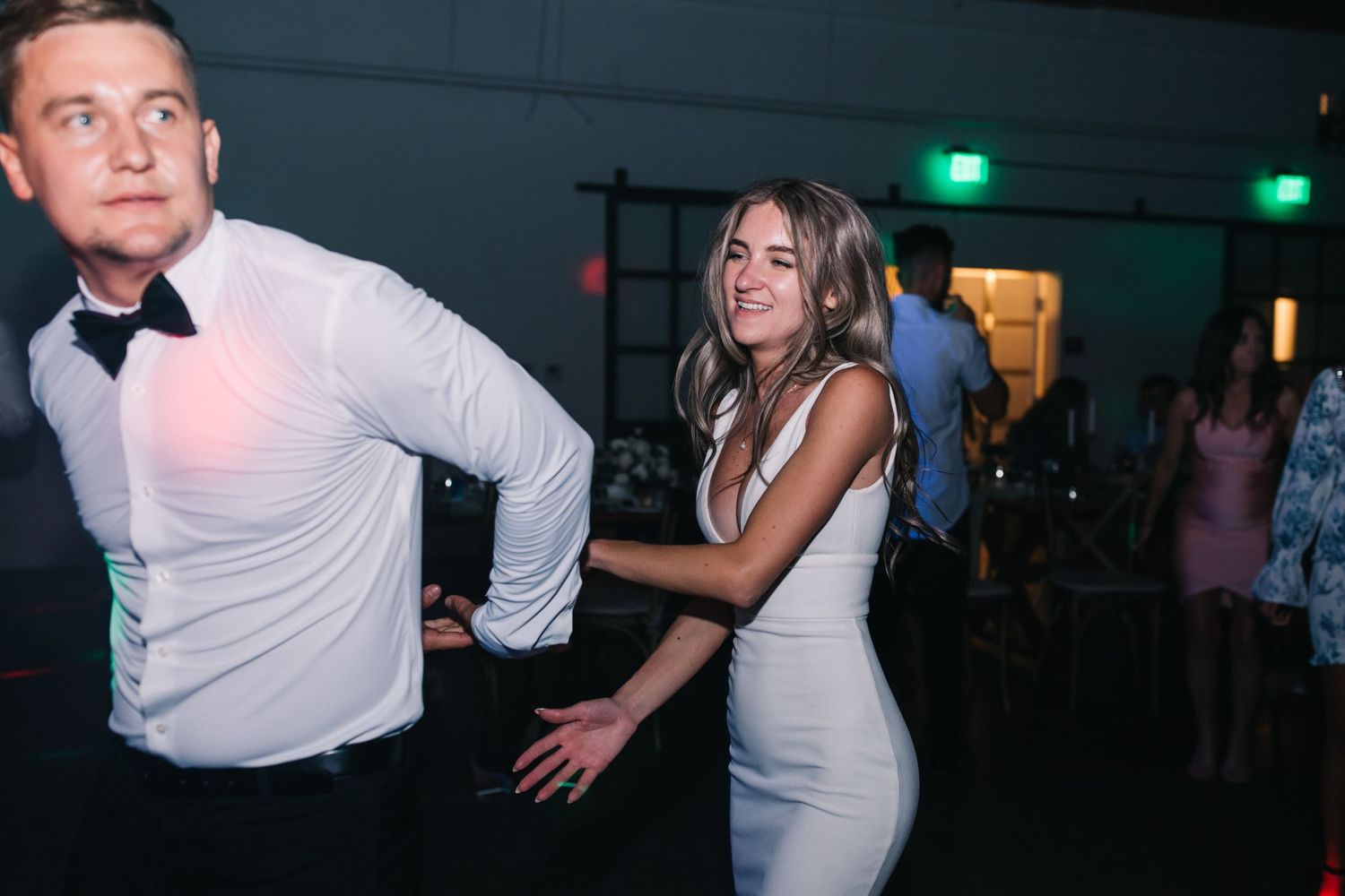 Lively dancing scene at wedding reception with guests in formal attire.