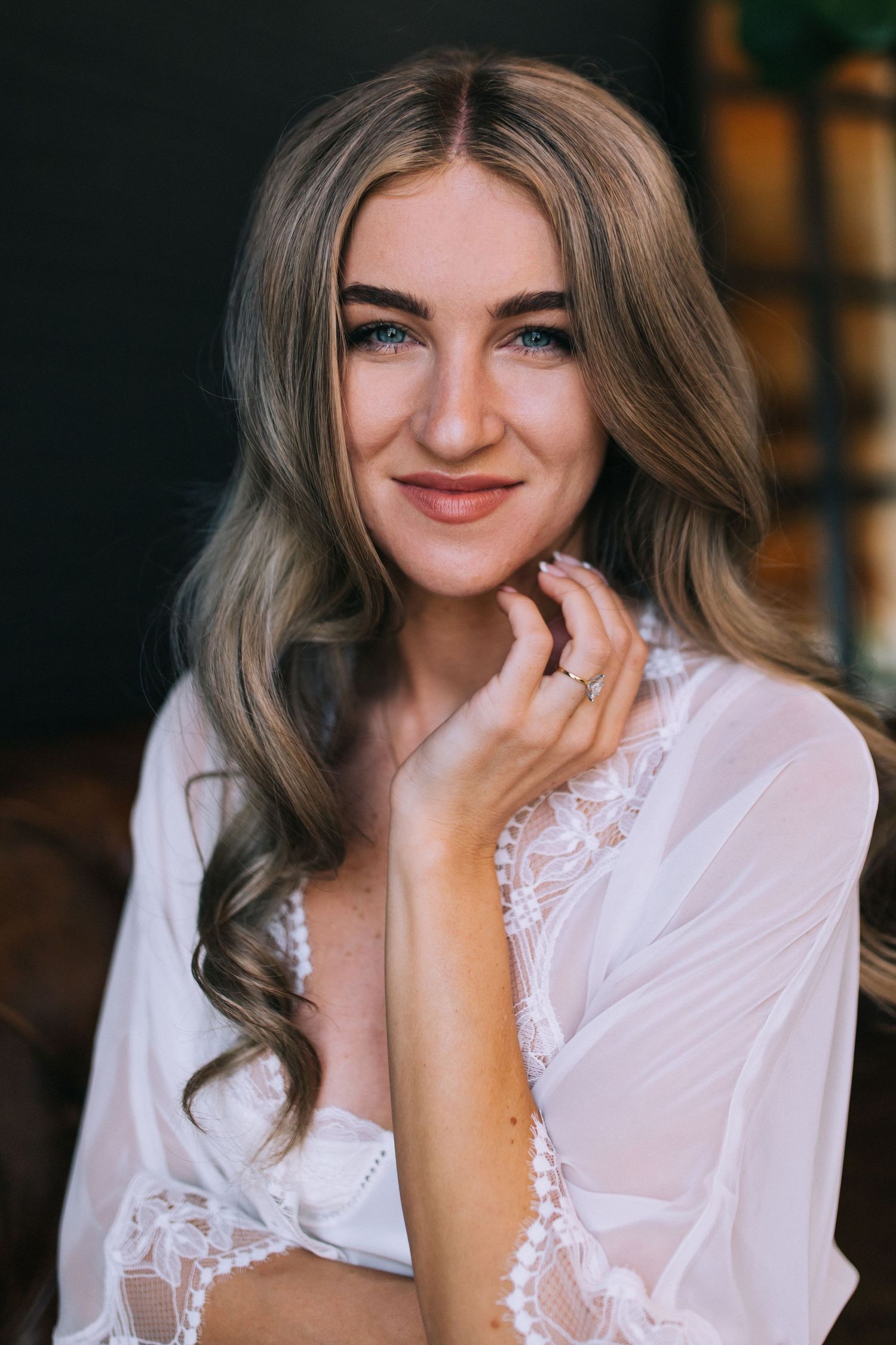 Close-up portrait of woman in white lace robe with ash blonde waves.