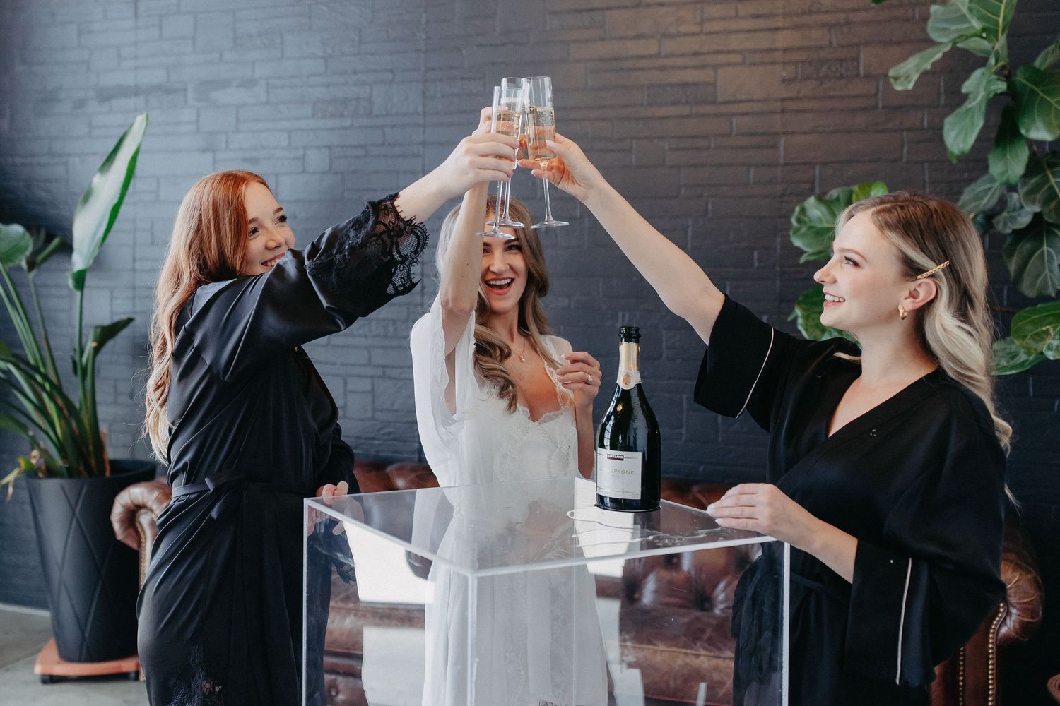 Group celebrating with champagne toast in modern room with dark walls.