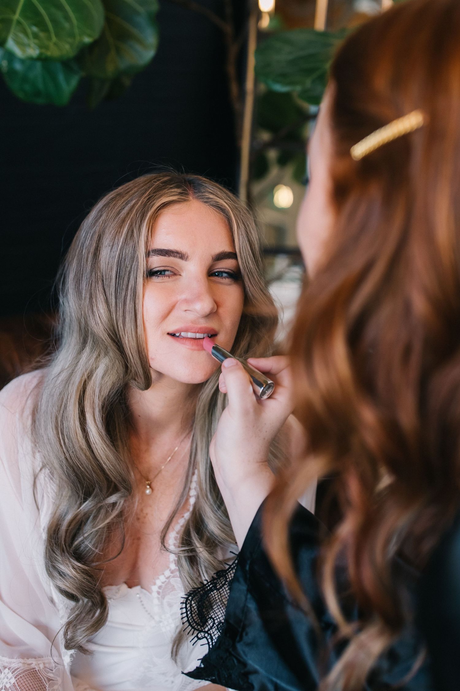 Makeup artist applies cosmetics during bridal preparation.