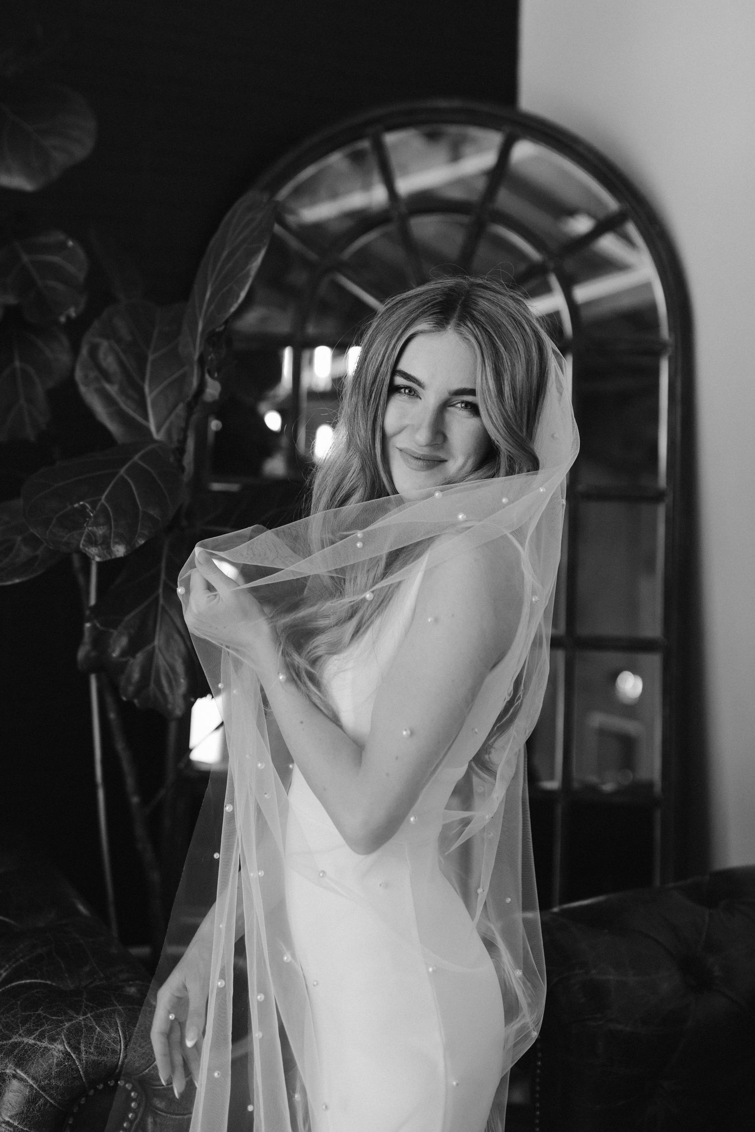 A black and white bridal portrait showing elegant details of the veil and gown.