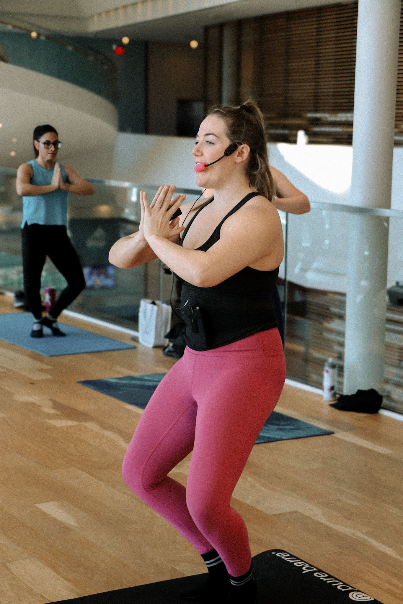 Group fitness class participants exercising in modern gym space.