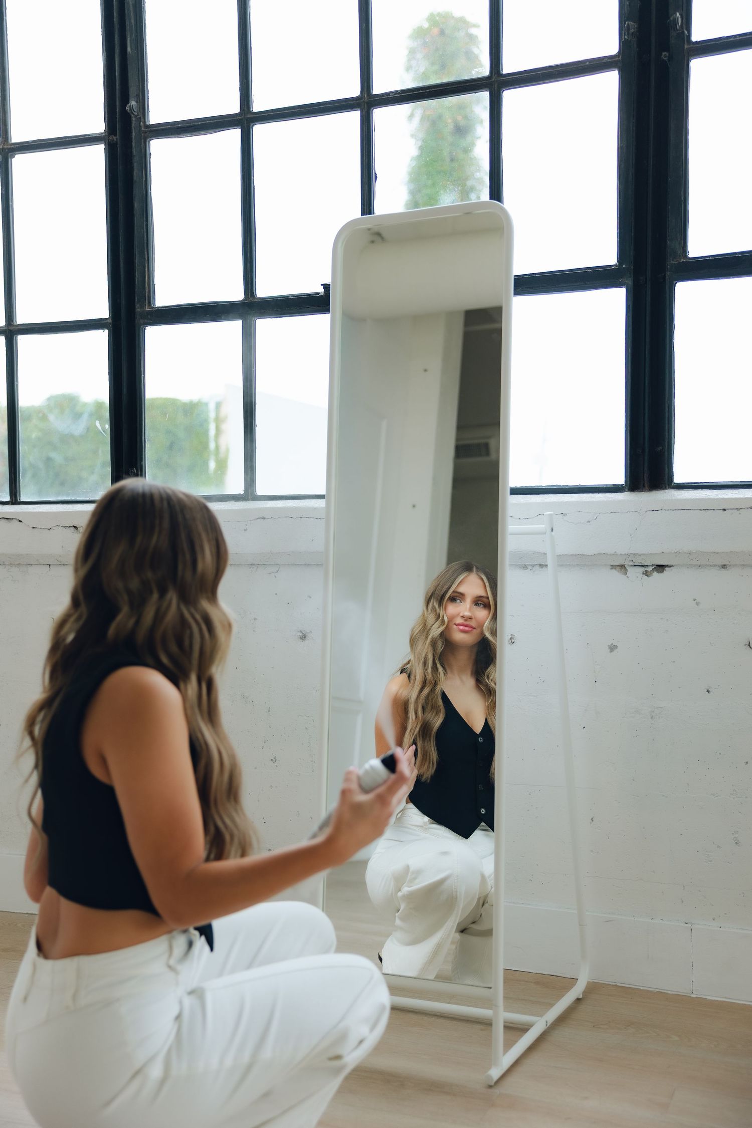 A bright studio space with mirrored walls shows multiple reflections of a person in black and white attire.