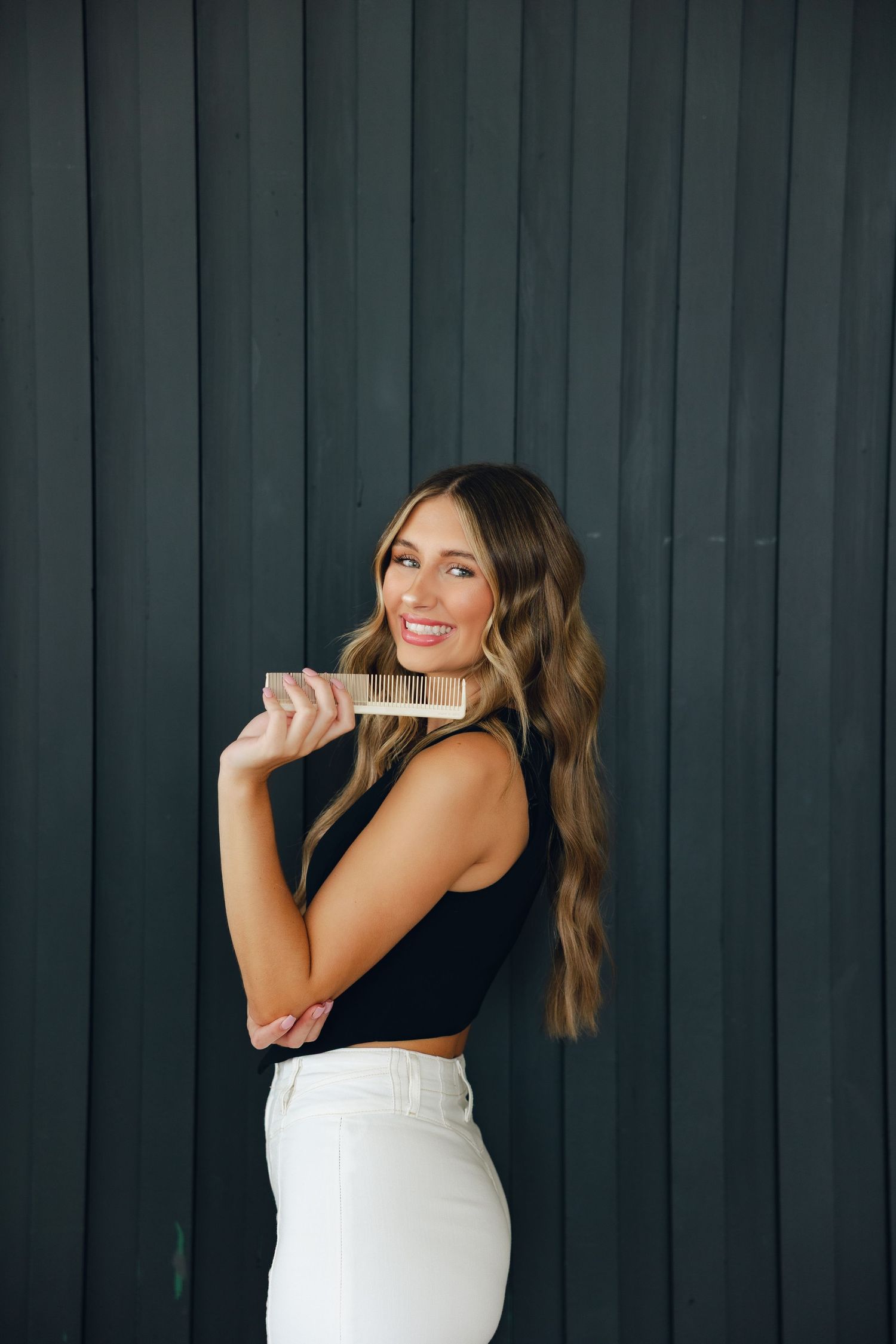 Woman in white dress and black top poses playfully against dark wall in sequence of four photos.