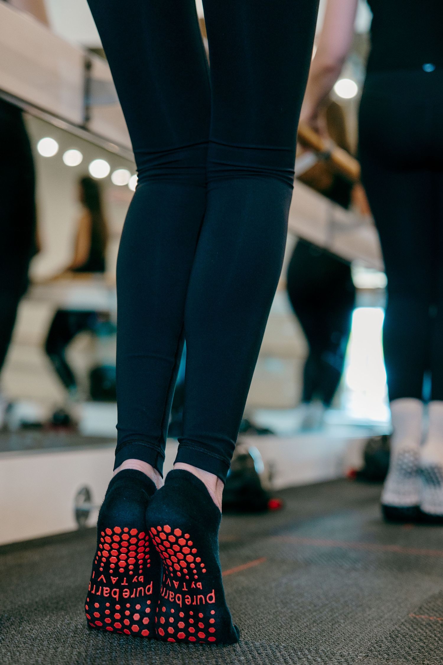 Close-up of black grip socks with red dots worn during a workout class.