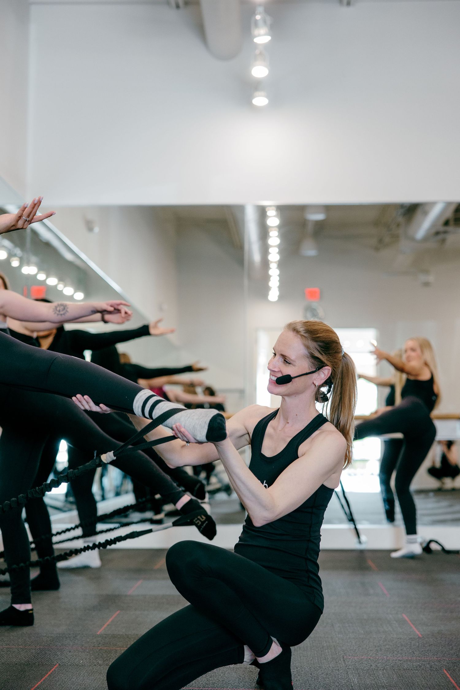 Fitness enthusiasts work out with weights during an exercise class in a bright studio setting.