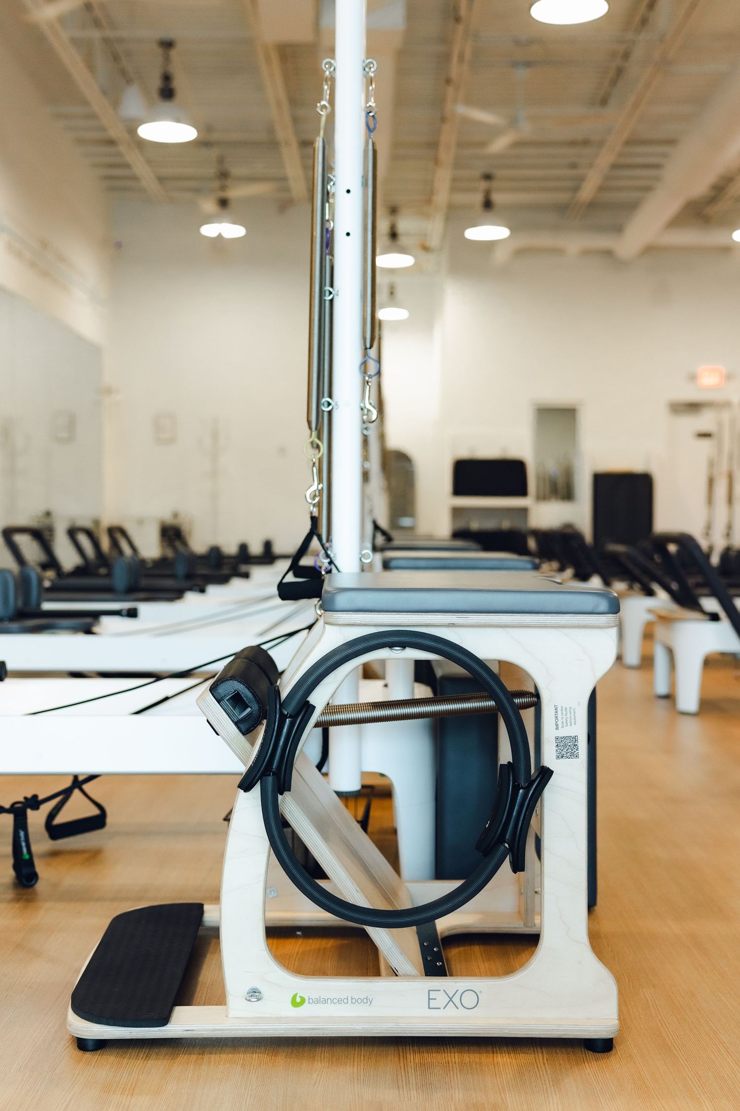 Modern white and black EXO rehabilitation equipment arranged in rows in a bright medical facility with wooden floors.