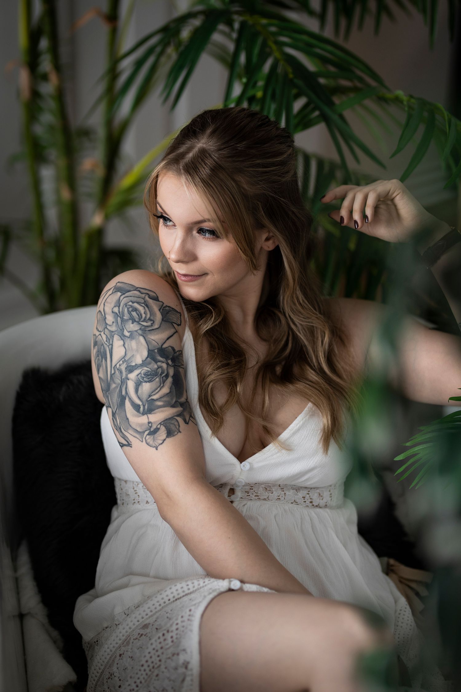 Intimate portrait with tropical plants showing detailed arm tattoo artwork.