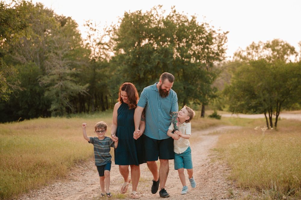 A family walks together on a dirt path during golden hour surrounded by nature.