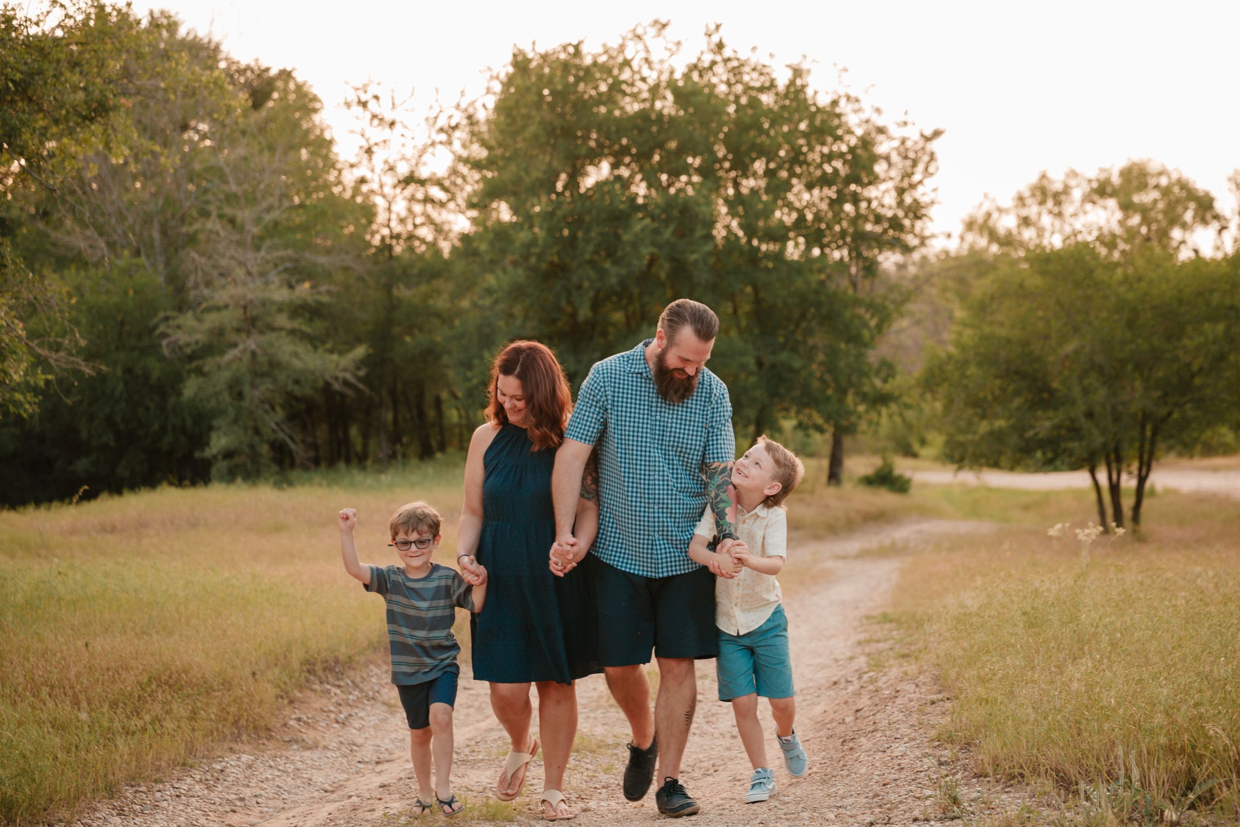 A family walks together on a dirt path during golden hour surrounded by nature.