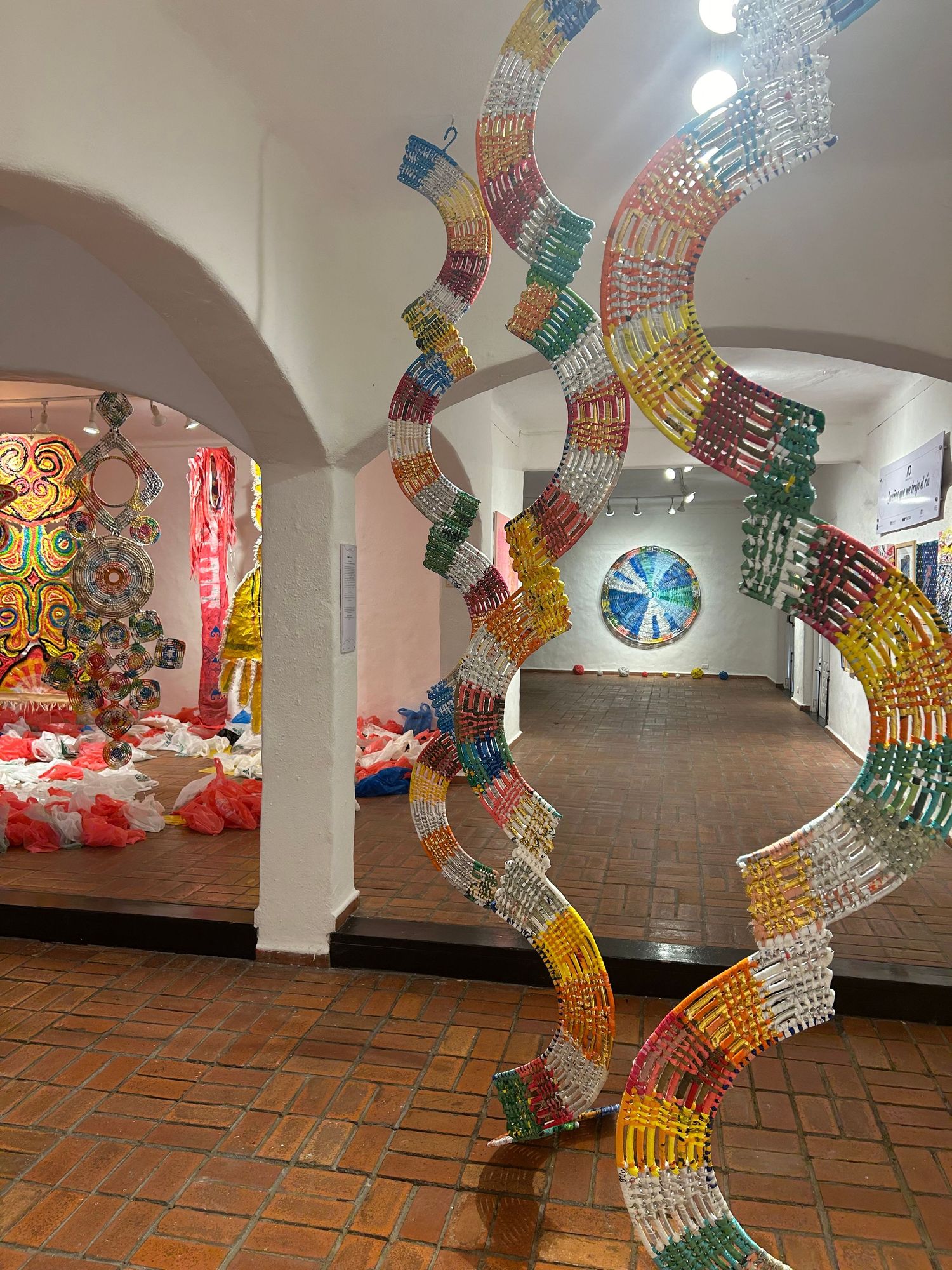 Gallery space with curved paper installations and circular artwork visible through archways.