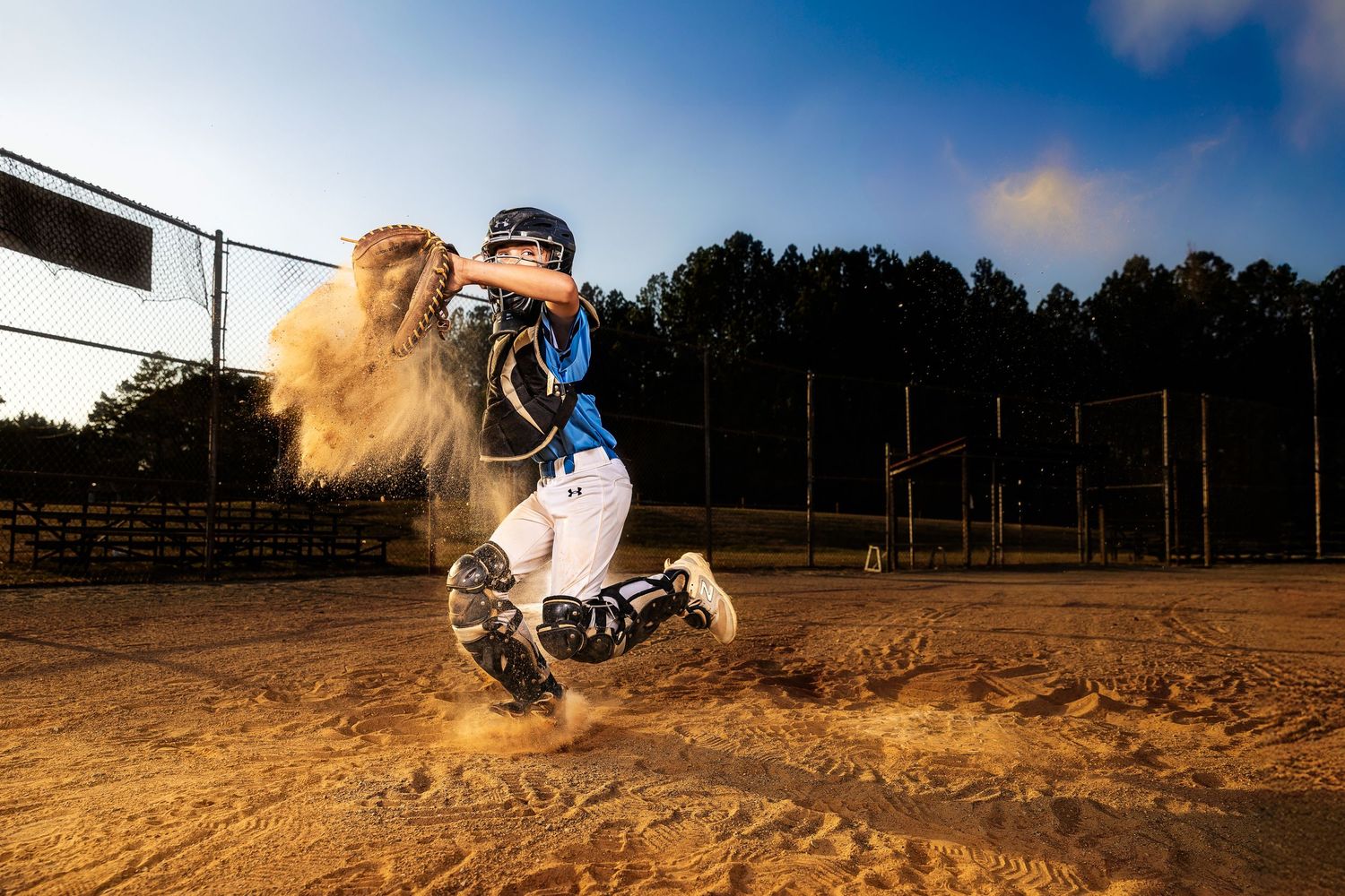 Baseball player performing diving catches and slides on a dirt field at sunset.