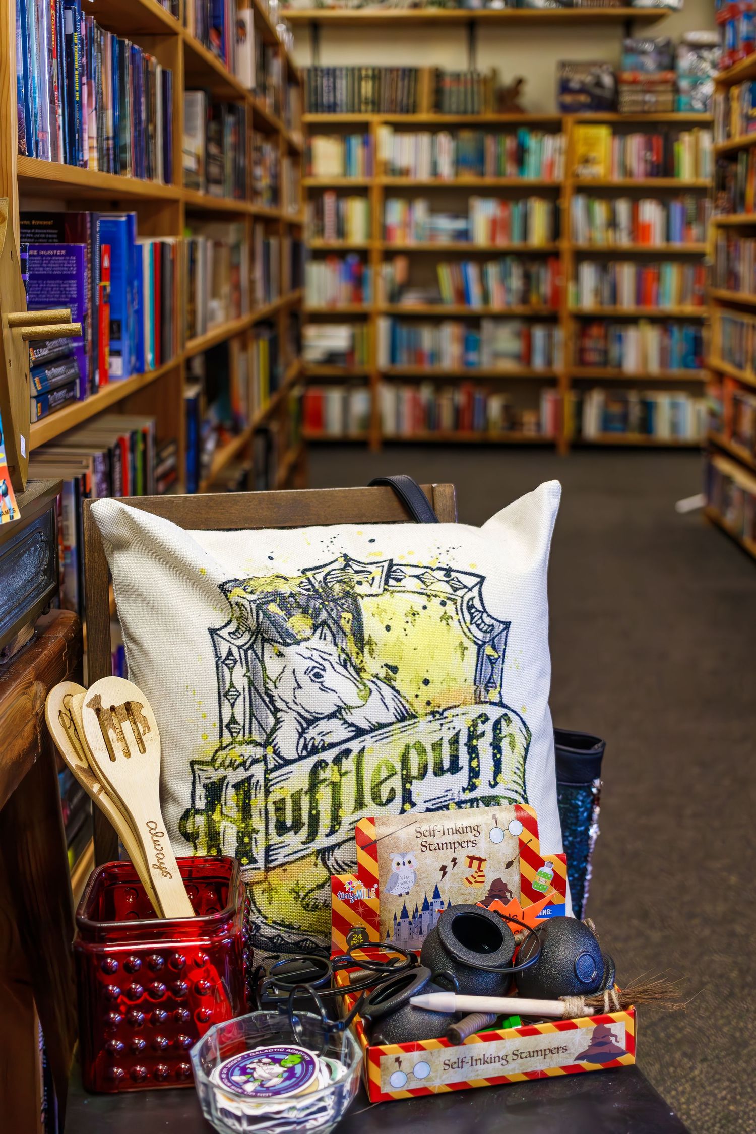 Harry Potter themed merchandise display with Hufflepuff pillow and wands in bookstore corner.